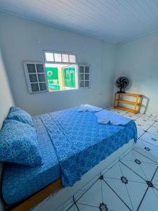 a bedroom with a bed with blue sheets and a window at Pousada Sempre Viva Lençóis in Lençóis