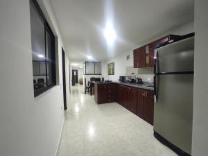 La cuisine est équipée d'un réfrigérateur en acier inoxydable et de placards en bois. dans l'établissement Apartamento con jacuzzi En Bello - Cerca a Medellín, à Bello
