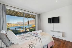 een slaapkamer met een bed en een groot raam bij Views On The Top - Queenstown Holiday Home in Queenstown