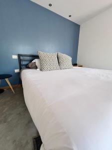 uma grande cama branca num quarto com uma parede azul em Bugambilias 203 Oaxaca em Oaxaca de Juárez