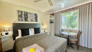 a bedroom with a bed and a table and a window at Golden Grain Motor Inn in Tamworth