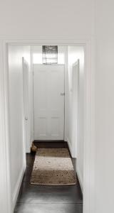 a hallway with white doors and a rug at The Dog House Cottage in Port Fairy