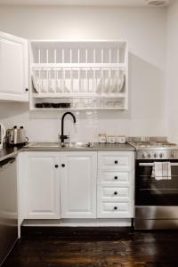 La cuisine est équipée de placards blancs, d'un évier et d'un four. dans l'établissement The Dog House Cottage, à Port Fairy