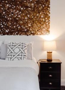 - une chambre avec un lit et une table de chevet avec une lampe dans l'établissement The Dog House Cottage, à Port Fairy
