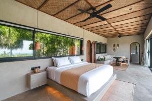 ein Schlafzimmer mit einem Bett und einem großen Fenster in der Unterkunft SIVANA, Hotel Boutique with ocean or garden views - Adults only in Uluwatu