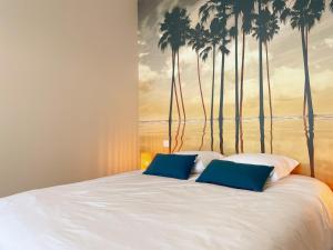 ein Bett mit einem Wandbild aus Palmen an der Wand in der Unterkunft Gîte tout confort pour 6-8 pers, cœur de village, parking privé, jardin clos, proche ZooParc de Beauval - FR-1-491-344 in Noyers-sur-Cher