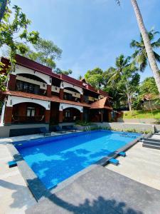 a resort with a swimming pool in front of a building at JEEVAN HOMESTAY kovalam in Kovalam