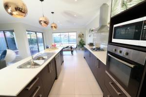cocina grande con fregadero y microondas en Designer Decor Home with 8Beds at Williams Landing, en Laverton