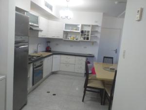 a kitchen with white cabinets and a table in it at Apartamento equipado frente de la bahía de pampatar in Pampatar