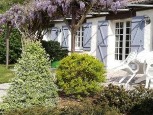 OislyにあるGîte familial au cœur des Châteaux de la Loire - FR-1-491-361の紫色の花が咲いた家の前に置かれた白い椅子