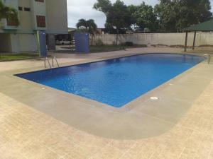 a large blue swimming pool on a tiled patio at Apartamento equipado frente de la bahía de pampatar in Pampatar