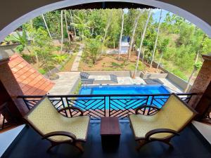 a balcony with two chairs and a table and a pool at Jeevan Homestay & Ayurvedic Yoga Retreat in Kovalam