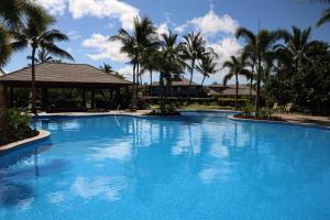 a large blue swimming pool with palm trees at SEASCAPE Delightful 3BR Detached KaMilo Home with Heated Pool in Waikoloa