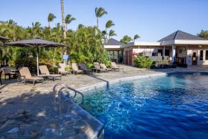 - un bassin profond dans un complexe avec des chaises et un parasol dans l'établissement THE POINT Contemporary 2BR Mauna Lani Point Home with Ocean View, à Waikoloa