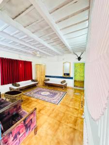 Coorg Heritage Hill View Resort في ماديكيري: غرفة معيشة كبيرة مع ستائر حمراء وأرضيات خشبية