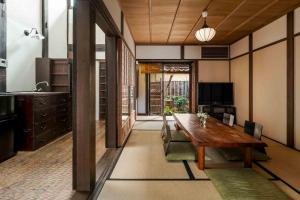 uma sala de jantar com uma mesa de madeira e uma cozinha em Hatoba an Machiya House em Quioto