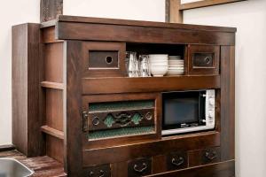 a wooden cabinet with a microwave and a tv at Hatoba an Machiya House in Kyoto