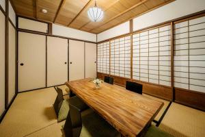 uma sala de jantar com uma mesa de madeira e cadeiras em Hatoba an Machiya House em Quioto