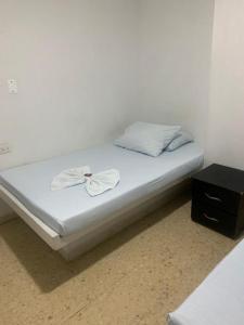 ein Bett mit weißer Bettwäsche und einem schwarzen Nachttisch in der Unterkunft Hotel La Fresa L&G in Pereira