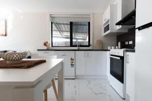 a white kitchen with white appliances and a table at Riverside Gem with Parking & WiFi in Alanvale