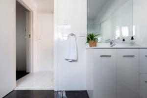 a white bathroom with a sink and a mirror at Riverside Gem with Parking and WiFi in Alanvale +14 photos