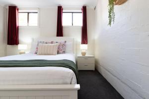 a white bedroom with a bed and two windows at Riverside Gem with Parking & WiFi in Alanvale