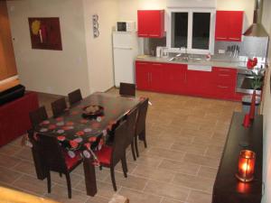 cocina con mesa, sillas y armarios rojos en Gîte Averdon, 4 pièces, 8 personnes - FR-1-491-377 en Averdon