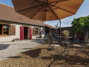 a table and chairs with an umbrella in front of a house at Gîte champêtre avec jardin, jeux pour enfants, animaux bienvenus - FR-1-491-390 in Cour-Cheverny +14 photos