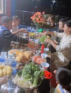 a group of people standing around a table with food at Khách Sạn Hùng Trang Hotel in Tam Ðảo