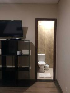 a bathroom with a toilet and a television at Apto individual com Garagem próx Petrobrás e Fiat in Betim