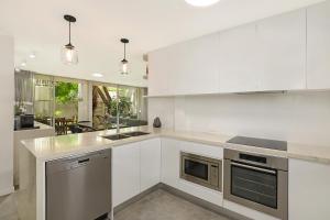 a kitchen with white cabinets and stainless steel appliances at Noosa Harbour Resort in Noosa Heads