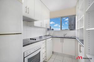 eine weiße Küche mit weißen Schränken und einem Fenster in der Unterkunft MetaWise Parramatta Chic and Comfortable Two Bed in Sydney