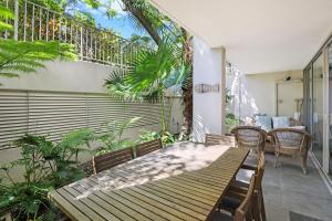 un patio con mesa de madera y sillas en Noosa Harbour Resort en Noosa Heads