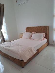 un letto con lenzuola bianche e cuscini rosa di Live Well Homestay Senawang a Seremban