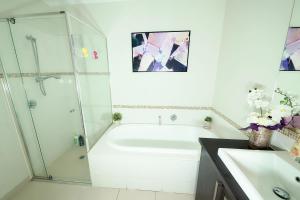 baño blanco con ducha y bañera blanca en Designer Decor Home with 8Beds at Williams Landing, en Laverton
