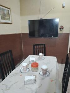 mesa con mantel blanco y TV en Mistela Altos de Mendoza- Con Wifi- Con Servicio Gratuito al Aeropuerto o la Terminal- en Godoy Cruz