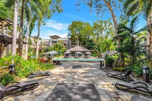een binnenplaats met een zwembad en bomen en een gebouw bij 'Tropical Escape' Coastal Daydreams with Rooftop Spa in Palm Cove