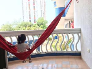 a little girl swinging in a hammock on a balcony at Apt 311 Mar de leva in Santa Marta