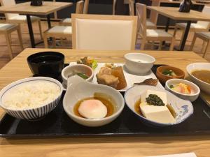 una bandeja de comida con tazones de comida en una mesa en Sauna & Capsule Hotel Rumor Plaza, en Kioto