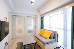 - un salon avec un canapé et un oreiller jaune dans l'établissement REBANGA Juso Apartment, à Osaka