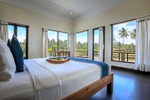een slaapkamer met een groot wit bed en ramen bij Nang Ade Villa by Pramana Villas in Ubud