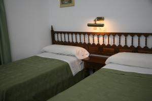 Hostal Santa Barbara في Socuéllamos: غرفة نوم بسريرين و اللوح الأمامي وطاولة
