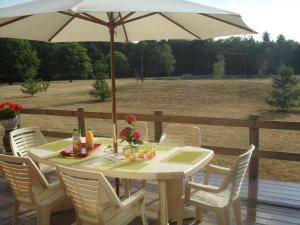 a white table and chairs with an umbrella on a deck at Maison spacieuse en Sologne avec grand jardin, proche randonnée, terrasse, parking privé - FR-1-491-437 in Chaon