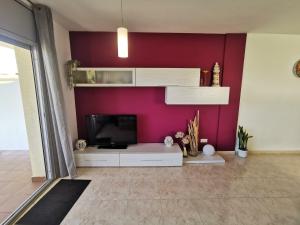 ein Wohnzimmer mit einem TV und einer lila Wand in der Unterkunft Apartamento Llançà, 2 dormitorios, 4 personas - ES-89-137 in Llança