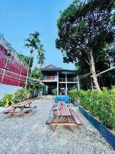 a group of picnic tables in front of a building at HOLY VILLA 4rooms, 5beds, 6baths, 1KCH, 1LR riverside private villa in Kampot