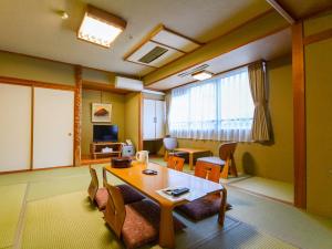 sala de estar con mesa, sillas y ventana en Hoshikawakan, en Yamanouchi