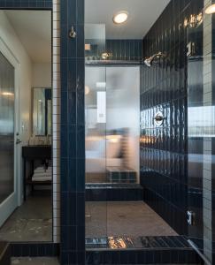 ein Bad mit einer Dusche mit schwarzen Fliesen in der Unterkunft Best Bet Motor Lodge in Reno