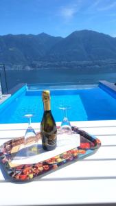 a bottle of wine and two wine glasses next to a swimming pool at Casa Makatea - b44831 in Brione sopra Minusio
