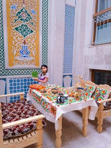 a young girl is sitting at a table with at Meros Hotel in Bukhara