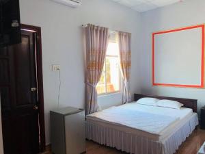 Bett in einem Zimmer mit einem Fenster und einem Bett sidx sidx sidx sidx in der Unterkunft KHÁCH SẠN ĐẾ VƯƠNG in Cao Lãnh